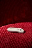 Witte Kobo afstandsbediening op een rode geribbelde bank, met de tekst 'Rakuten Kobo'.