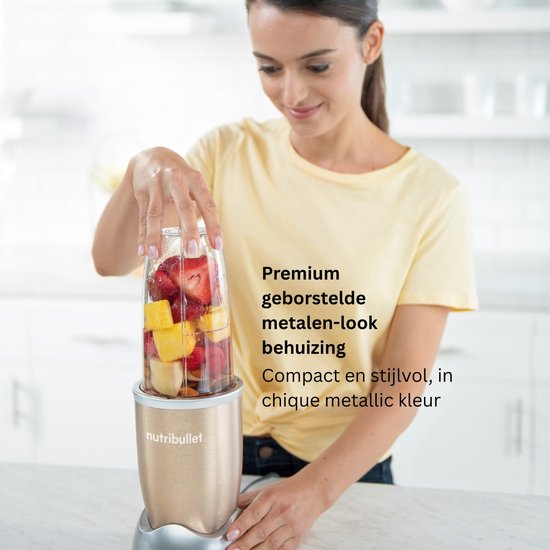 Vrouw met gele top met Nutribullet blender in champagnekleur. De beker is gevuld met fruit.
