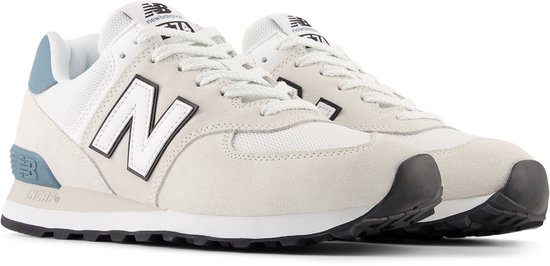 Paire de baskets New Balance 574 blanches en daim et mesh. Logo 'N' blanc et noir sur le côté. Détails bleus sur le talon.