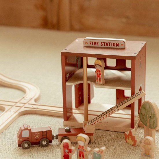Houten brandweerkazerne met "FIRE STATION"-bord, brandweerwagen, poppetjes en een ladder.