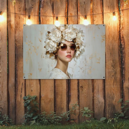 Een vrouw met een grote witte bloemenkrans op haar hoofd en een gouden zonnebril.
