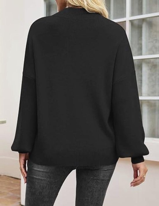 Achterkant van een zwarte gebreide trui met pofmouwen en hoge hals, gedragen met een grijze jeans.