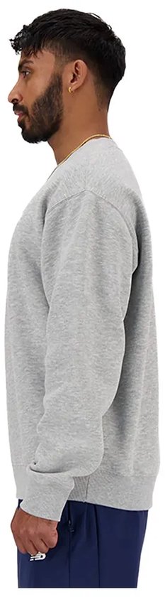 Zijaanzicht van een man in een grijze New Balance sweater.