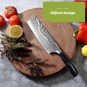 Couteau de chef à motif damassé avec manche noir sur une planche à découper en bois, entouré de tomates fraîches, citron, poivron et légumes. "Design élégant"