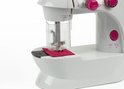 Detailopname van de naald en stof op de witte kindernaaimachine met roze accenten.