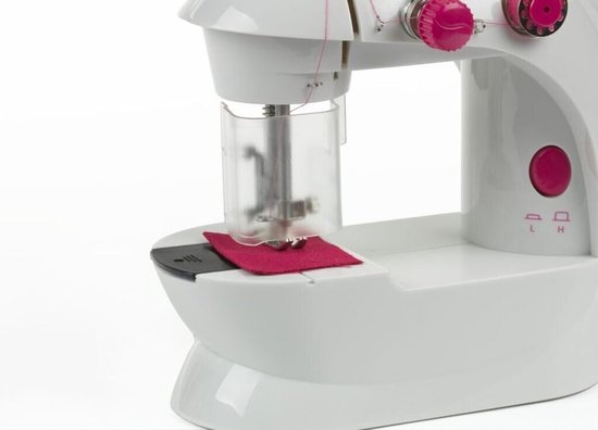 Detailopname van de naald en stof op de witte kindernaaimachine met roze accenten.