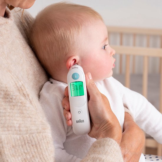 Een baby wordt gemeten met de Braun oorthermometer. Het scherm toont 37.1°C.