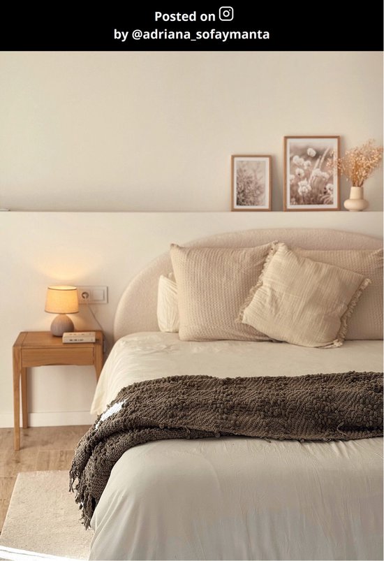 Petite lampe avec base grise et abat-jour orange sur une table de nuit à côté d'un lit.