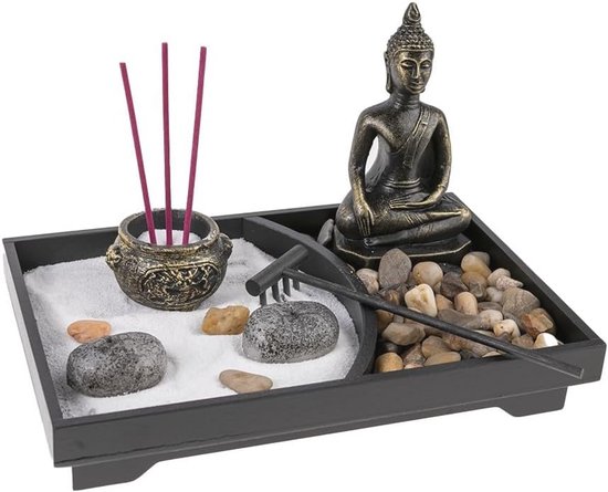 Zen tuin met Boeddhabeeld, wierookhouders met rode wierookstokjes, stenen en een harkje.