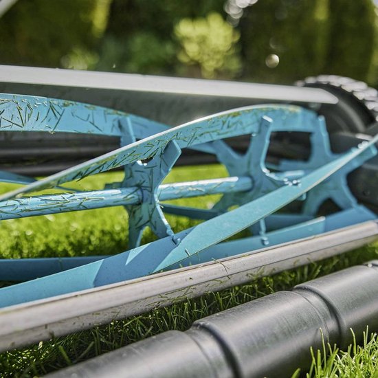 Close-up van het blauwe maaimechanisme van een GARDENA kooimesmaaier op groen gras.