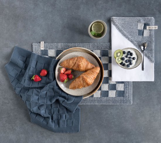 Grijze deken met vierkante patronen, naast grijze geruite placemats.