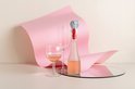 Grijze olifant wijnstopper op een fles, met roze papier en een spiegel.