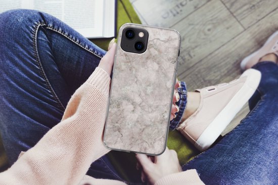 Persoon houdt iPhone 13 hoesje met marmerprint vast, zittend.