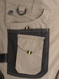 Salopette beige avec bouton STØRVIK, boucle et une poche noire avec boucle jaune et noire.