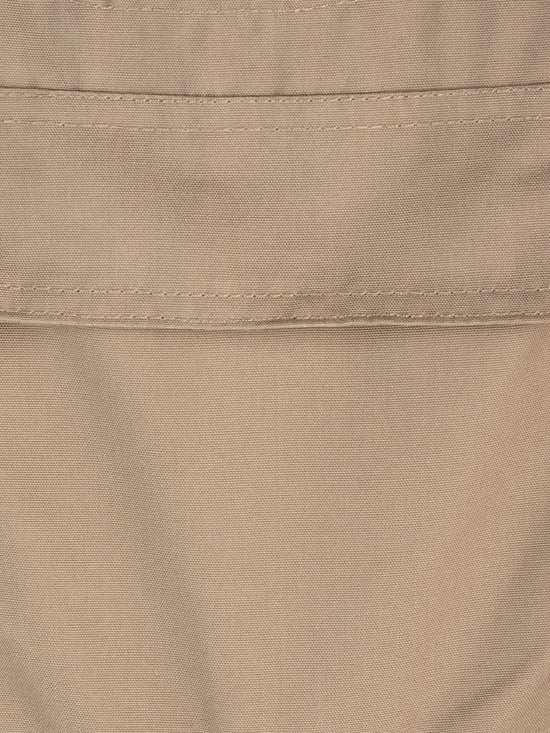 Détail de tissu beige d'une salopette, avec des coutures.