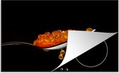 KitchenYeah® Inductie beschermer 78x52 cm - Rode kaviaar op een lepel met een zwarte achtergrond - Kookplaataccessoires - Afdekplaat voor kookplaat - Inductiebeschermer - Inductiemat - Inductieplaat mat
