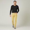 Man met een glimlach draagt een zwarte longsleeve en een gele corduroy broek. Hij draagt zwarte sneakers.