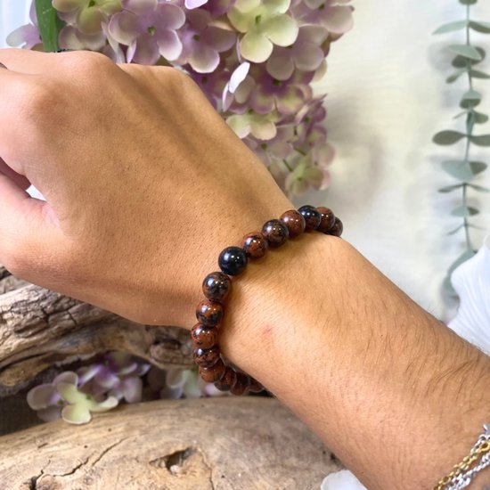 Mahonie obsidiaan kralen armband op een arm, met bruine, zwarte en rode tinten.