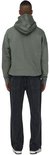 Een man draagt een grijze hoodie van katoen en een zwarte jeans, rug naar de camera.