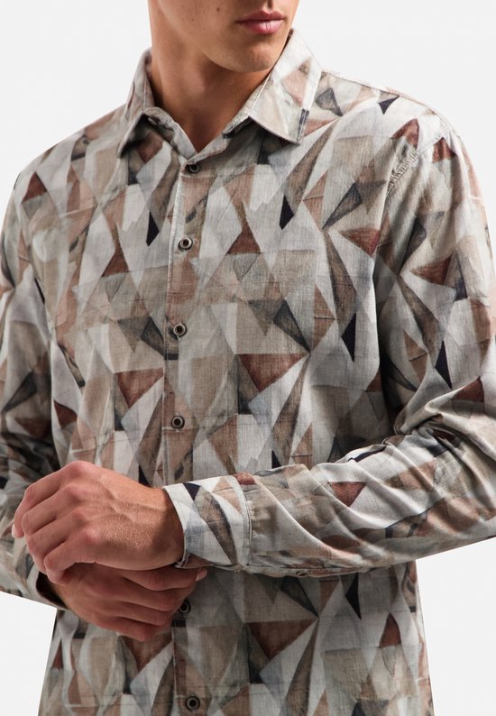 Model draagt een overhemd met all-over geometrische print in bruin-, grijs- en wittinten op corduroy.