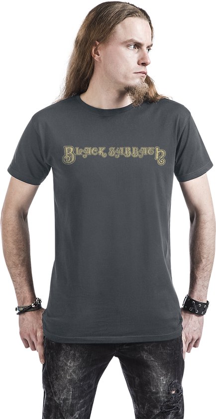 Homme aux longs cheveux portant un t-shirt gris foncé avec le nom du groupe "Black Sabbath" en doré, écrit en lettres cursives sur le devant.