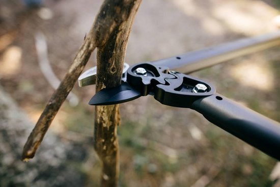 Detailopname van een Fiskars takkenschaar die een tak doorknipt.