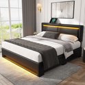 Zwart bed met beddengoed en gele LED-verlichting, naast raam met uitzicht op tuin.