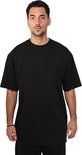 Man gekleed in een oversized zwart t-shirt en zwarte broek, staand, van voren gezien.