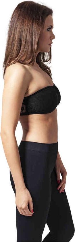 Zijaanzicht van model in zwarte kanten bandeau top en zwarte legging.