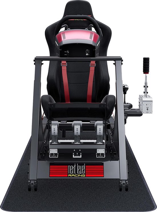 Next Level Racing GT Track Cockpit racestoel met zwarte zitting, rode veiligheidsgordels, pedalen en versnellingspook.