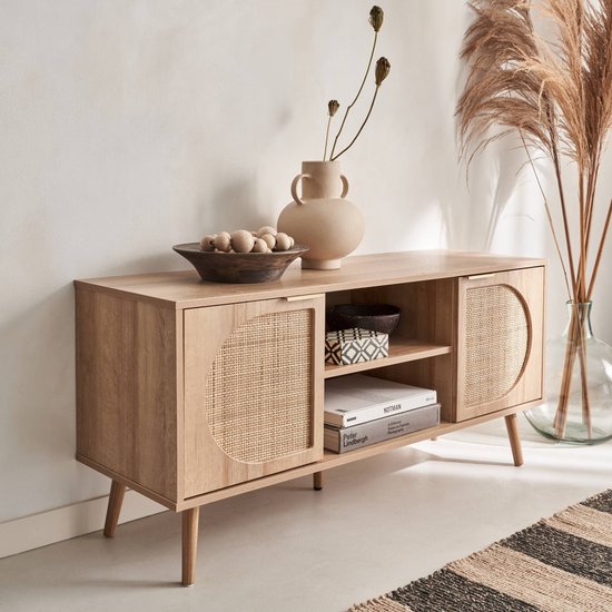 Tv-meubel van houtdecor met ronde rieten deuren, een open middenvak met legplank en schuine pootjes.