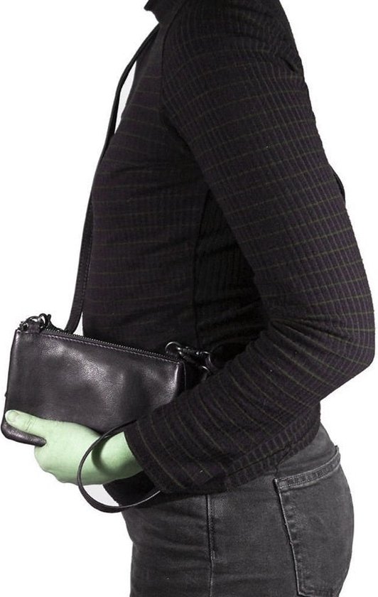 Zwarte leren clutch met polsbandje, gedragen door een model met een zwart gestreept shirt.