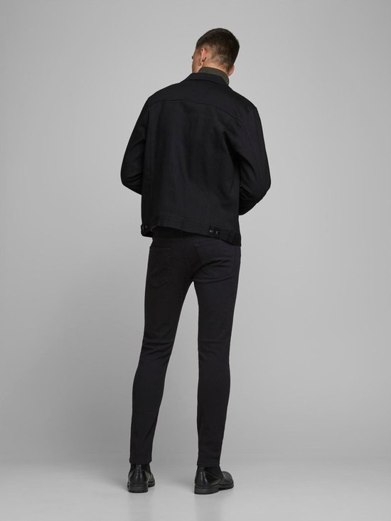Achterkant van een man in zwarte skinny jeans en zwarte jas.