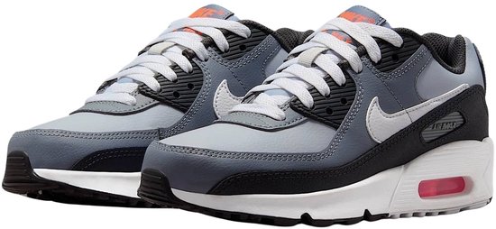 Grijze Nike Air Max 90 sneakers met witte veters, zwarte en witte details, en rode accenten.