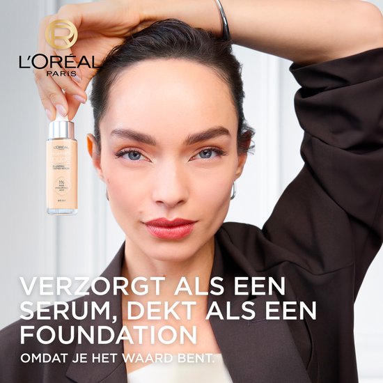 Een vrouw met een lichte huid en bruine jas houdt een flesje L'Oréal Paris foundation vast.