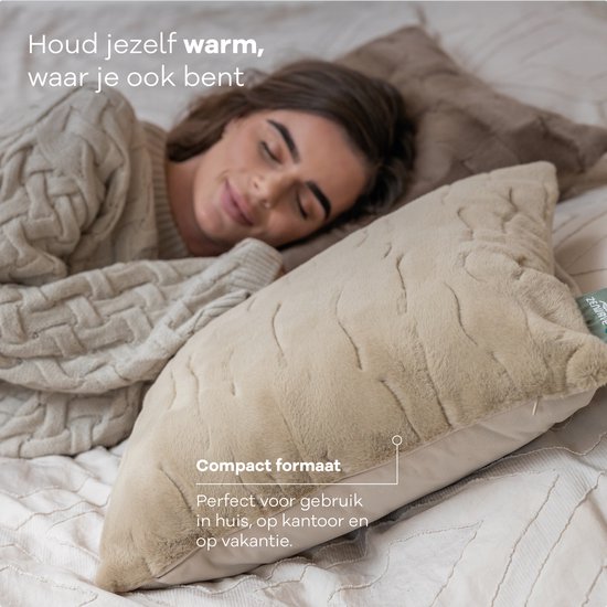 Vrouw met trui omarmt een Sandstone Beige Zenwave warmtekussen. Compact formaat, perfect voor thuis, kantoor of vakantie.