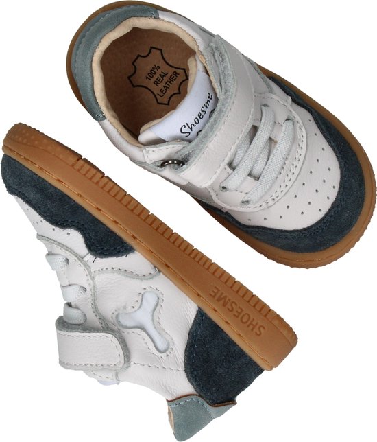 Twee witte leren sneakers met donkerblauwe suède details en bruine zolen.