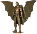 Gouden actiefiguur van Batman met vleermuisvleugels en jetpack, staand op een sokkel.