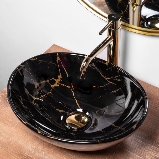Lavabo ovale noir avec imprimé marbre et veines dorées, robinetterie dorée.