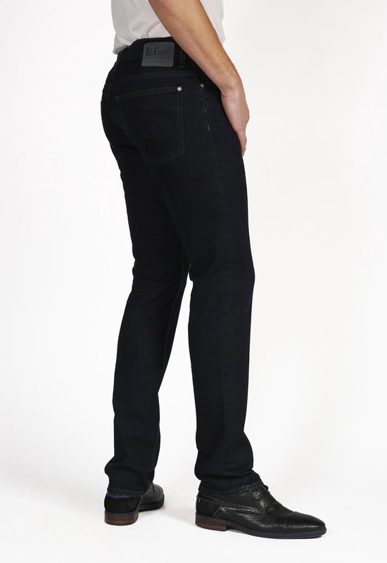 Man in donkere Lee Cooper jeans, staand van opzij naar achter, witte shirt, donkere schoenen.