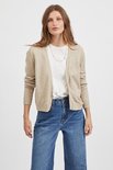Lichtbeige gebreid vest met lange mouwen, gedragen over een wit shirt, jeans en ketting.