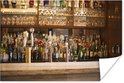 Close-up van een bar met veel flessen drank en glazen, met een marmeren blad.