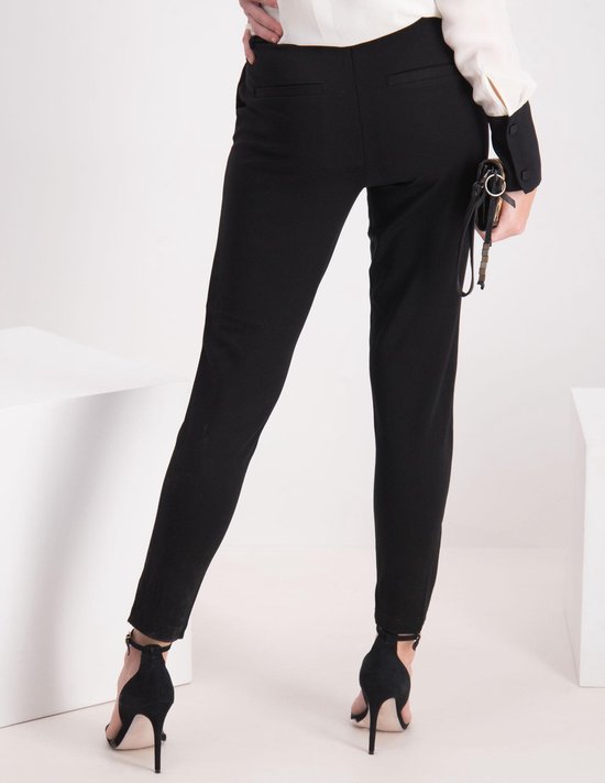 Zwarte broek met hoge taille, gedragen door een model met zwarte pumps en een tasje.