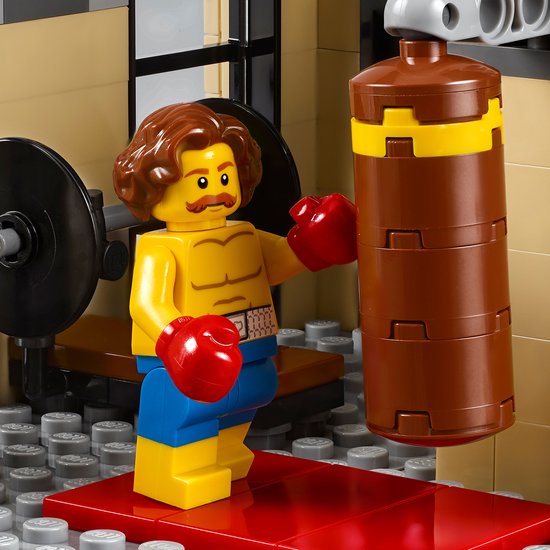 LEGO minifiguur bokser met bruin haar, snor, rode bokshandschoenen en blauwe short, traint op een bokszak.
