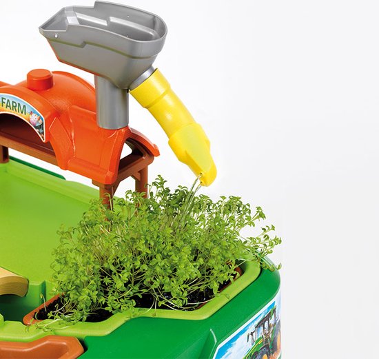 Close-up van de John Deere boerderij speeltafel: water stroomt uit een gele trechter in een bakje met cress.