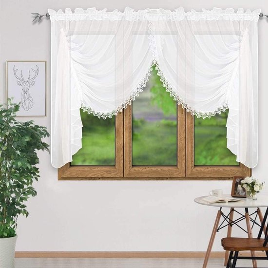 Witte voile vitrage met decoratieve kantranden en ruches, hangend voor een raam met houten kozijnen.