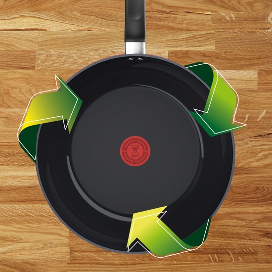 Zwarte Tefal pan op houten ondergrond met drie groene recycle-pijlen die de rand volgen.
