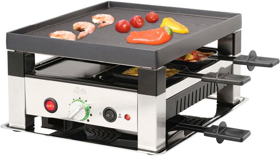 Zilverkleurige raclette grill met gegrilde bovenplaat met garnalen, tomaten en paprika. Onderin pannetjes met eten.