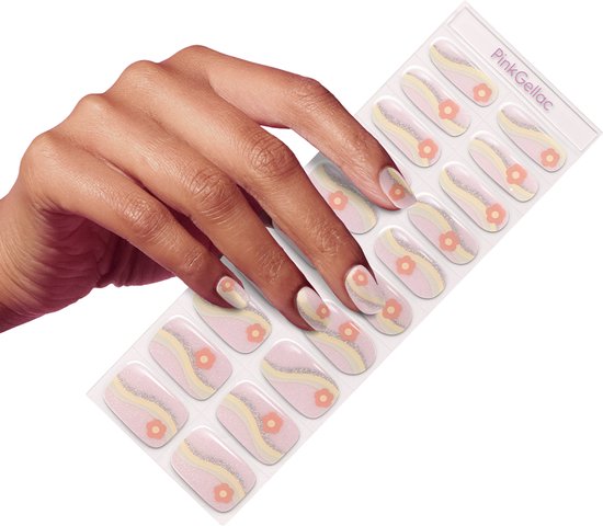 Hand met een donkere huidskleur die een nagelsticker met roze golven, gele strepen en oranje bloemen met glitter aanbrengt.