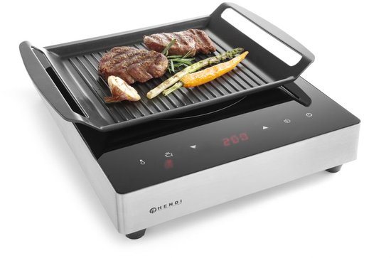 Inductie grillplaat met digitale display, waarop twee steaks, asperges, wortel en knoflook gegrild worden.